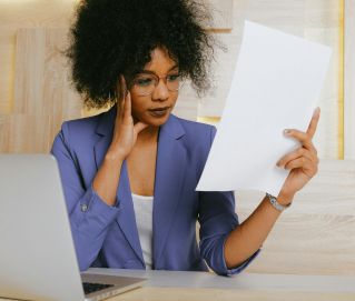 Businesswoman working on a laptop and reviewing a document at the office.